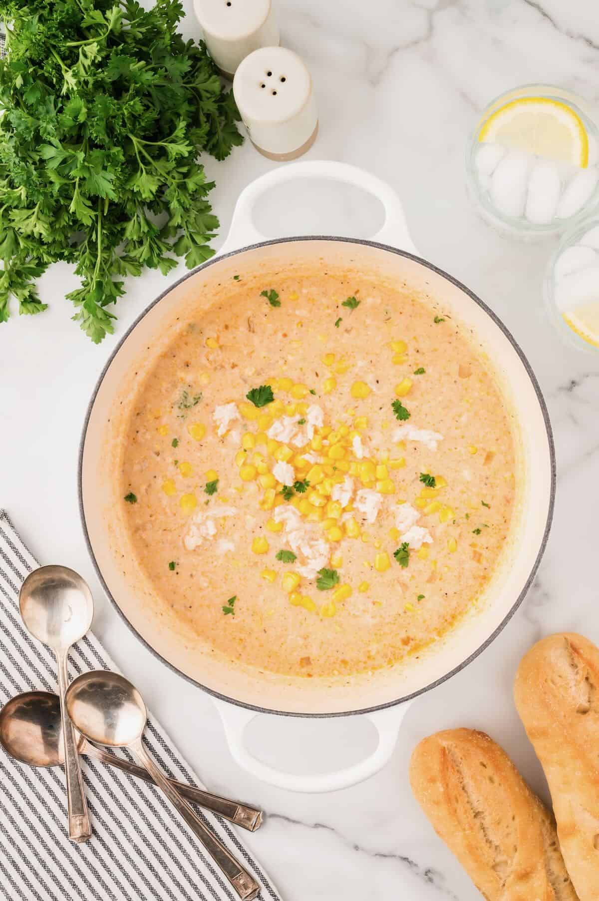 A large white Dutch oven full of corn and crab bisque.