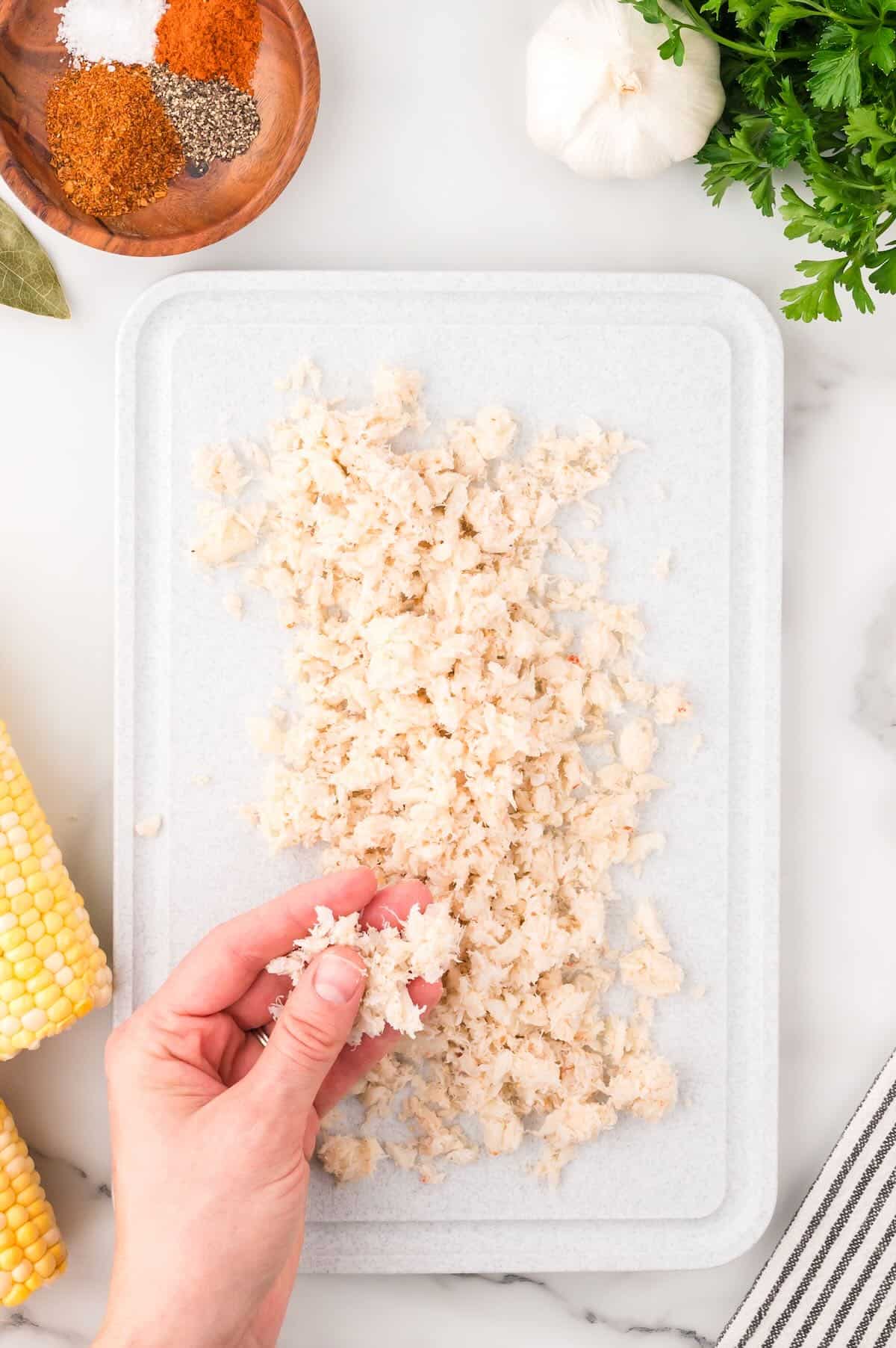 Crabmeat spread out on a cutting board to see if there are any bits of shell in it. 
