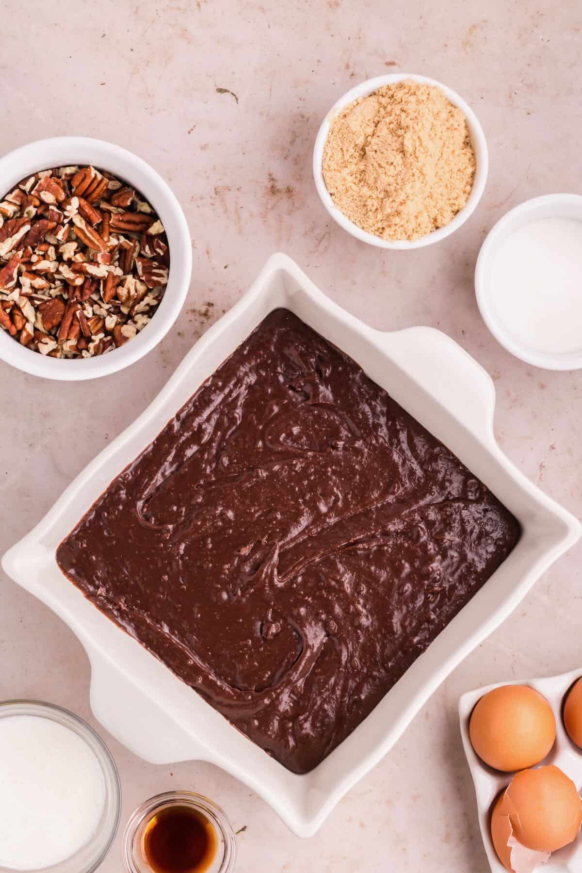 A white square baking dish full of brownie batter.