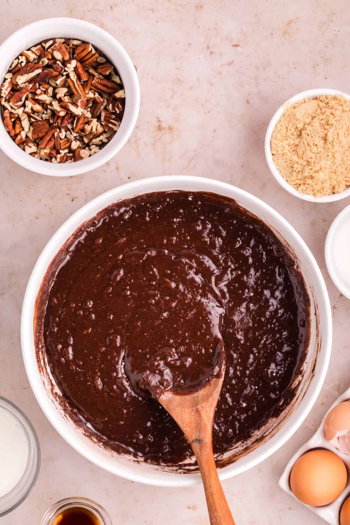 Brownie batter in a mixing bowl with a wooden spoon.
