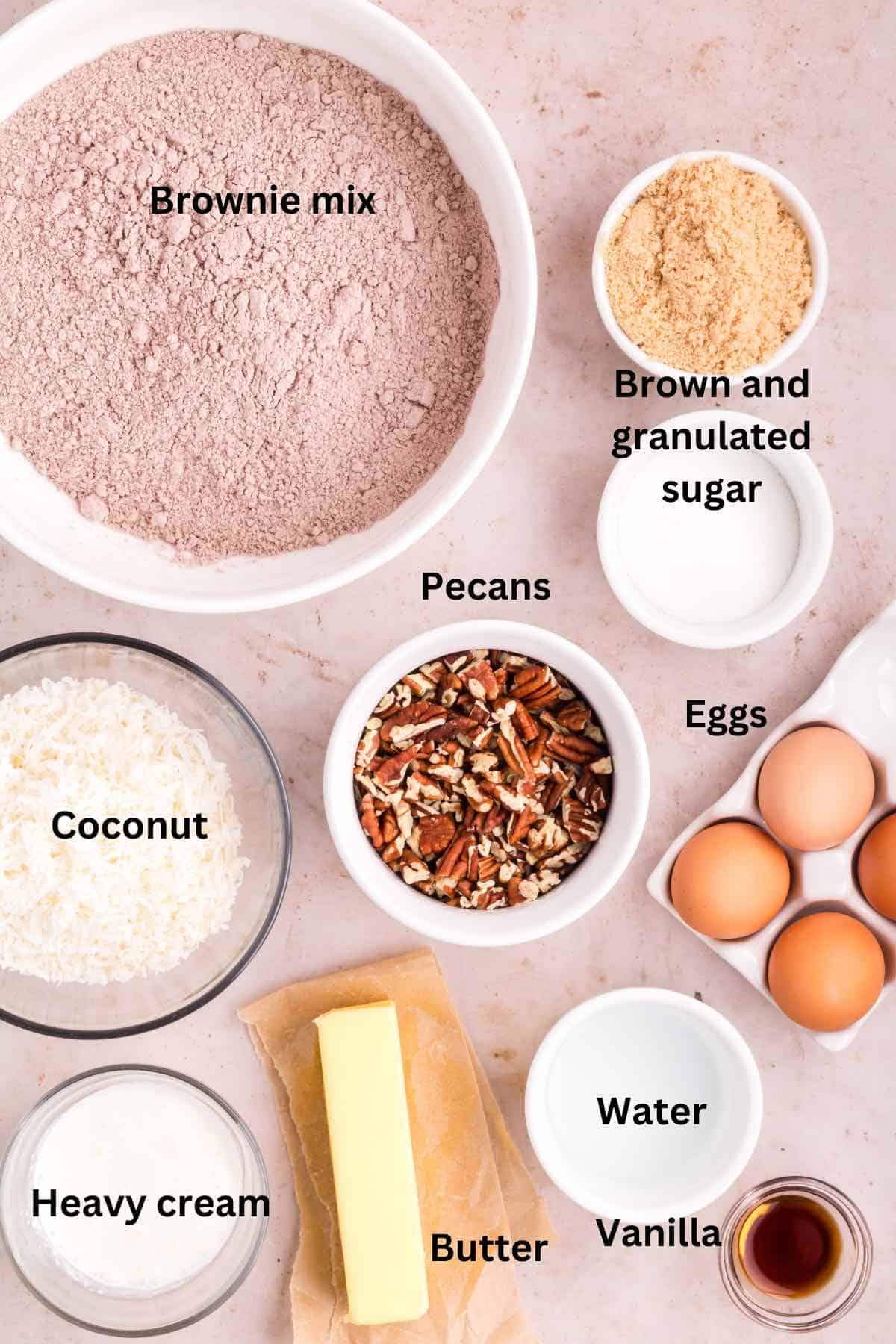 Ingredients for German chocolate brownies on a table include brownie mix, coconut, and pecans. 