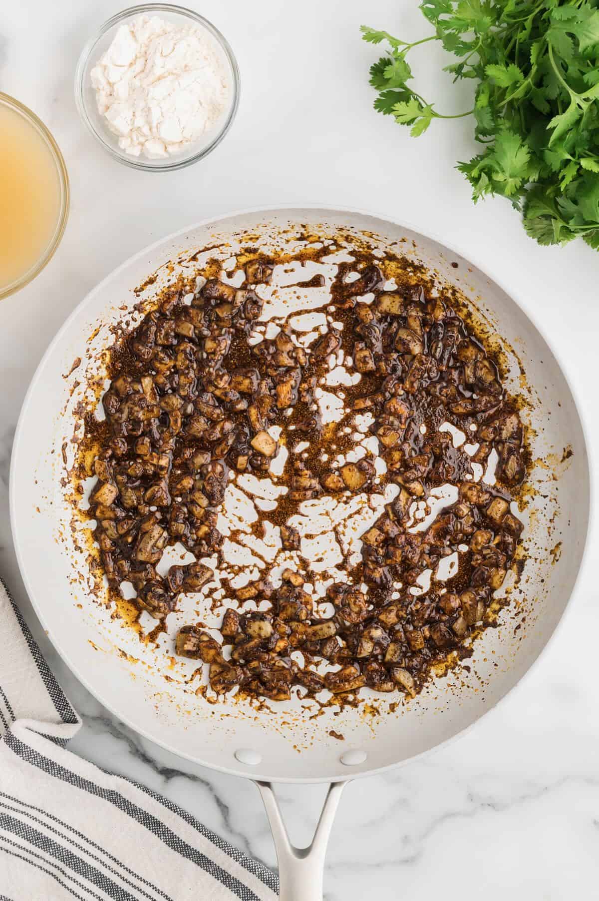 Cooked diced onions, garlic, and cumin in a skillet. 