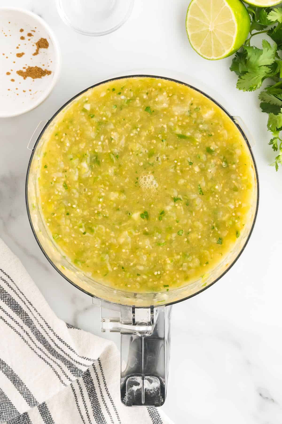 A food processor bowl full of salsa verde. 