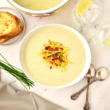 A bowl of Irish Potato Soup topped with cheese, chives and bacon.