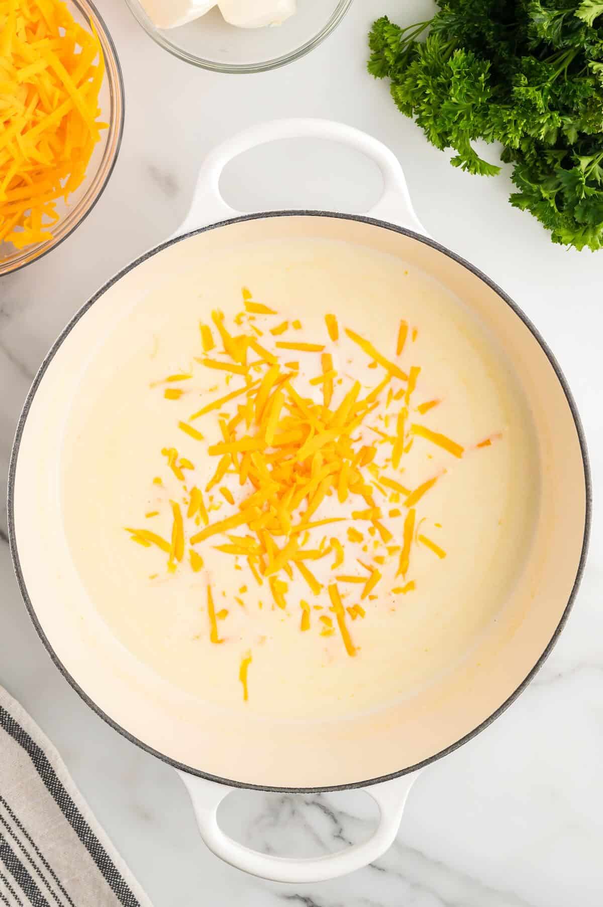 A bechamel sauce for making mac and cheese in a large pot with cheese added. 