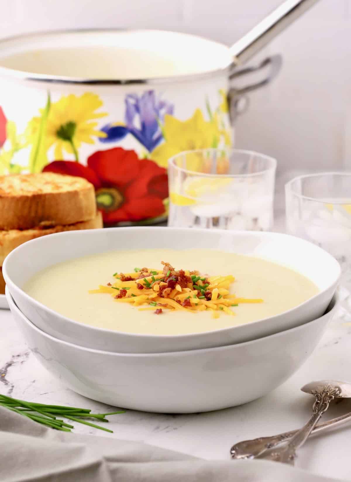 A large bowl of Irish Potato Soup topped with shredded cheese, bacon, and chives.