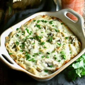 Turkey noodle casserole in a baking dish topped with melted cheese and chopped parsley.