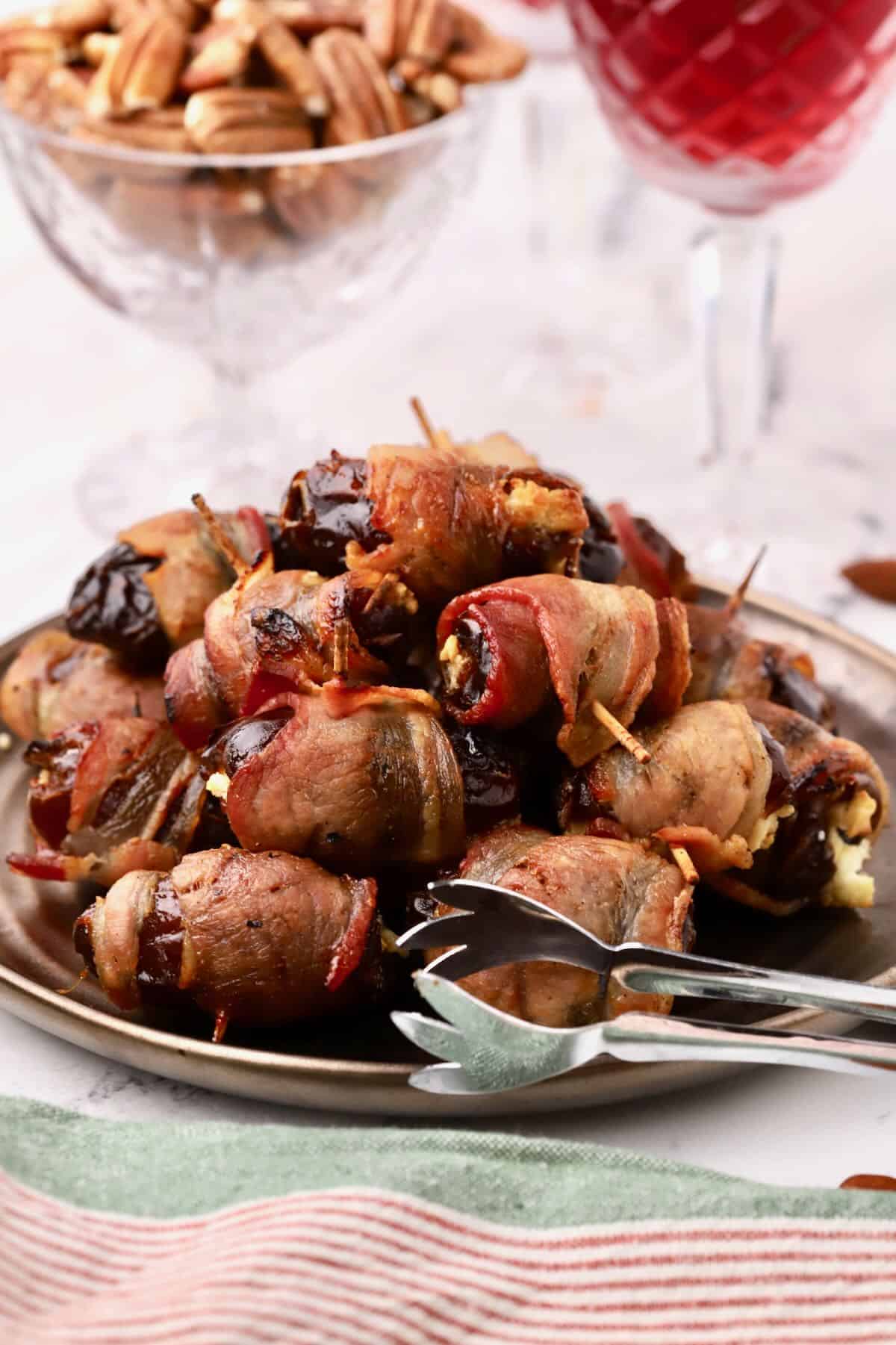 Bacon-wrapped stuffed dates on a bronze plate.