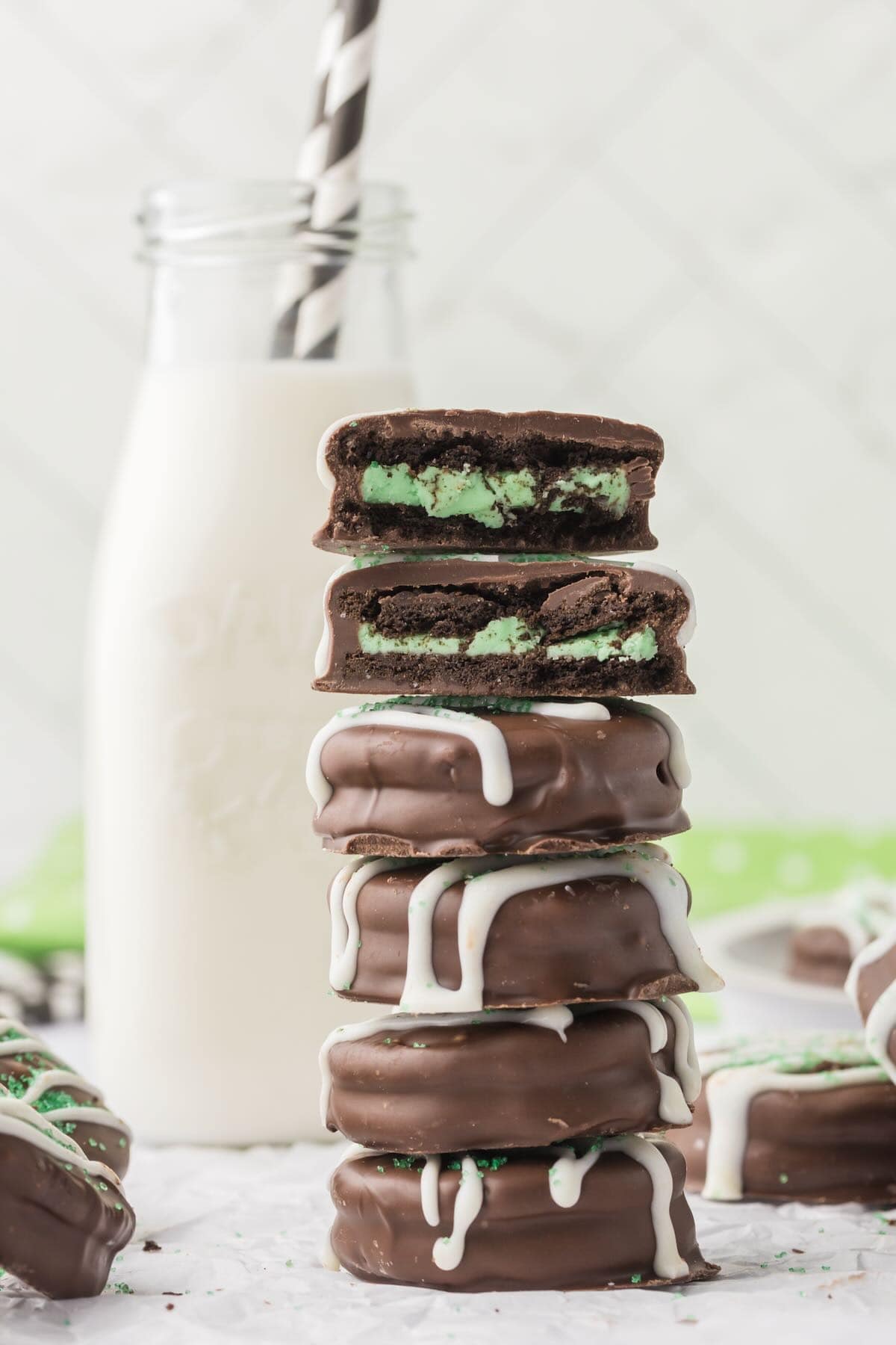 A stack of chocolate-covered mint Oreos next to a bottle of milk. 
