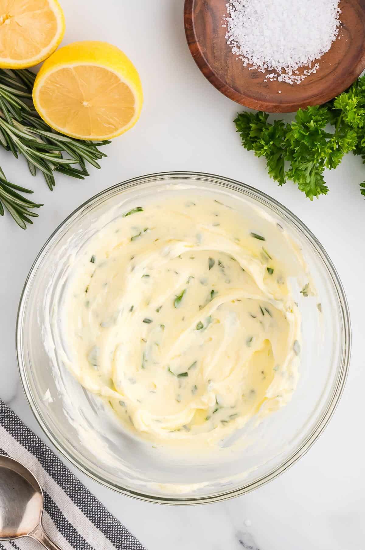Garlic herb butter in a clear glass bowl. 