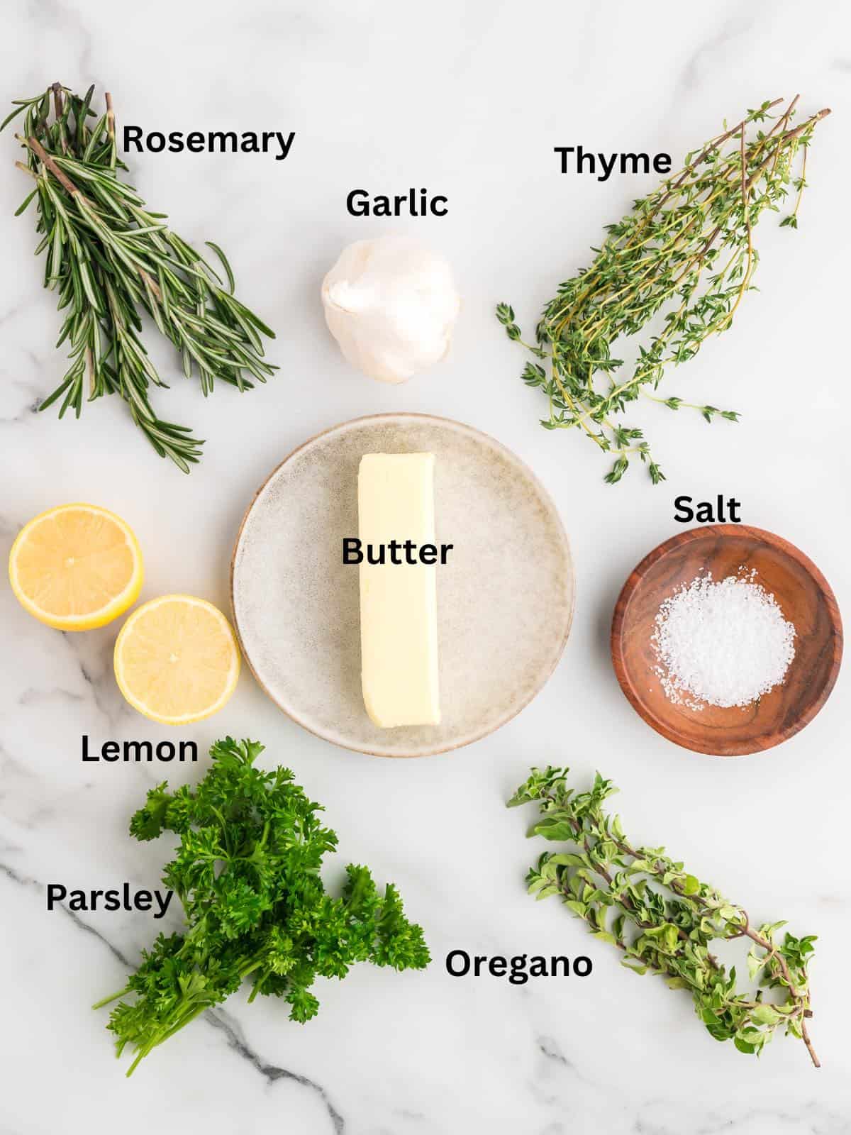 A stick of butter, fresh herbs, lemons and salt to make garlic herb butter.