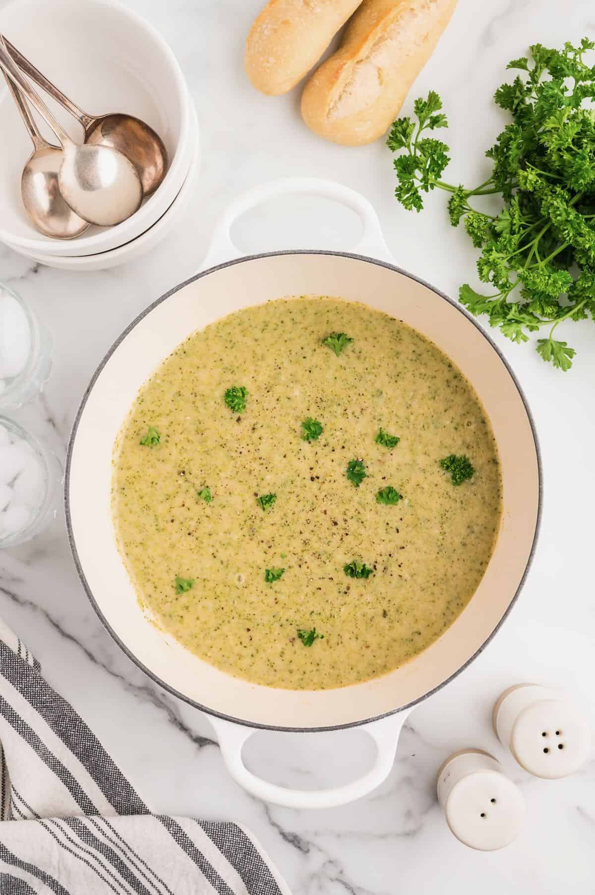 A large white soup pot full of pureed broccoli and white bean soup.