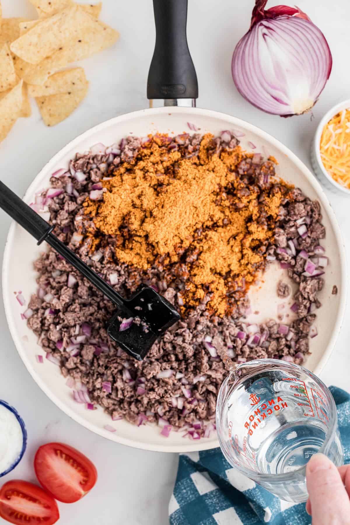 Ground beef cooking in a white skillet. 