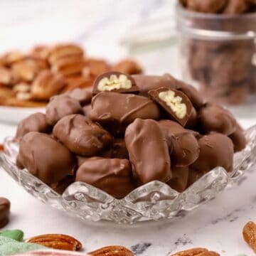 Chocolate covered pecans in a clear cut glass dish.