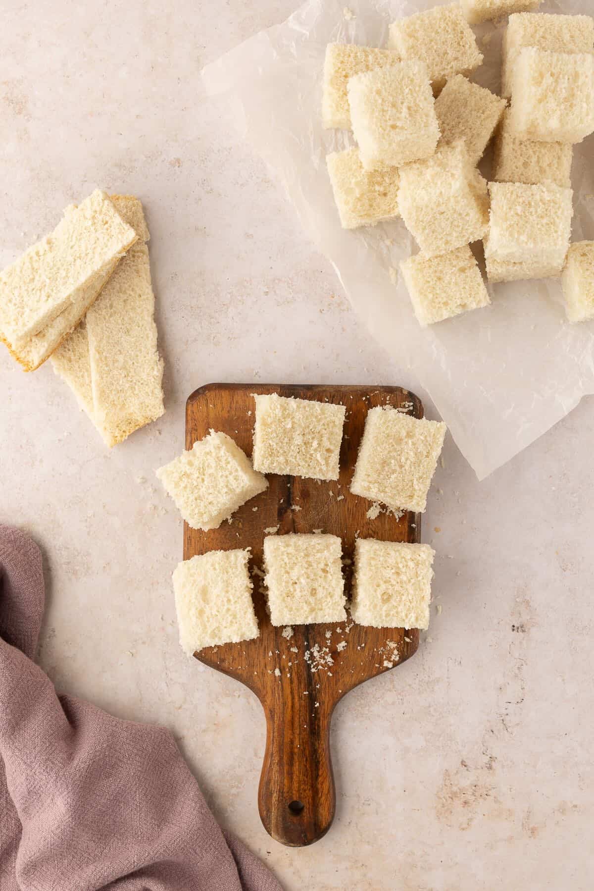 Bread cut into cubes on a cutting board. 