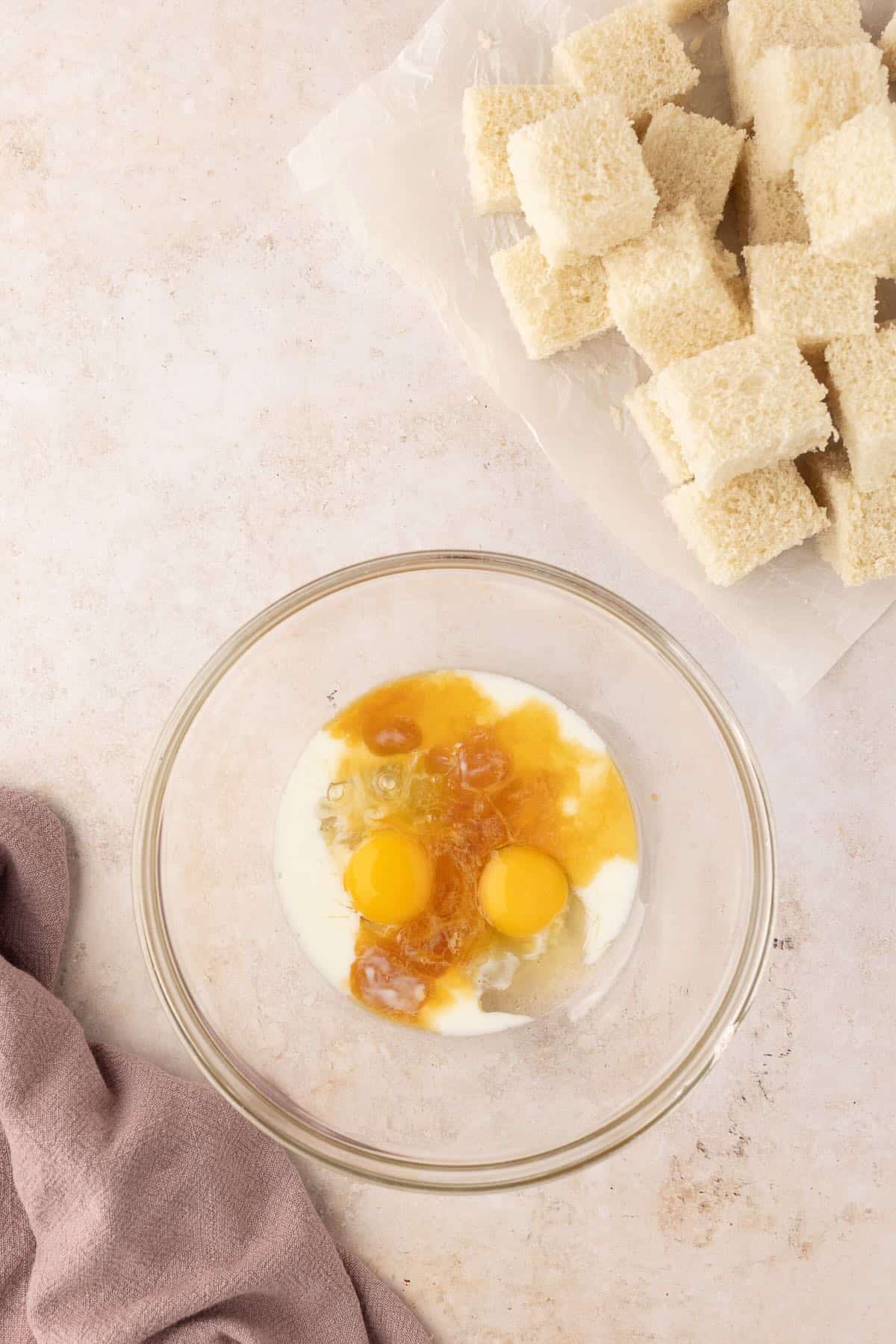 Eggs, milk, and vanilla extract in a clear glass bowl. 
