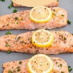 Pinterest pin showing four salmon fillets on a baking sheet topped with lemon slices.