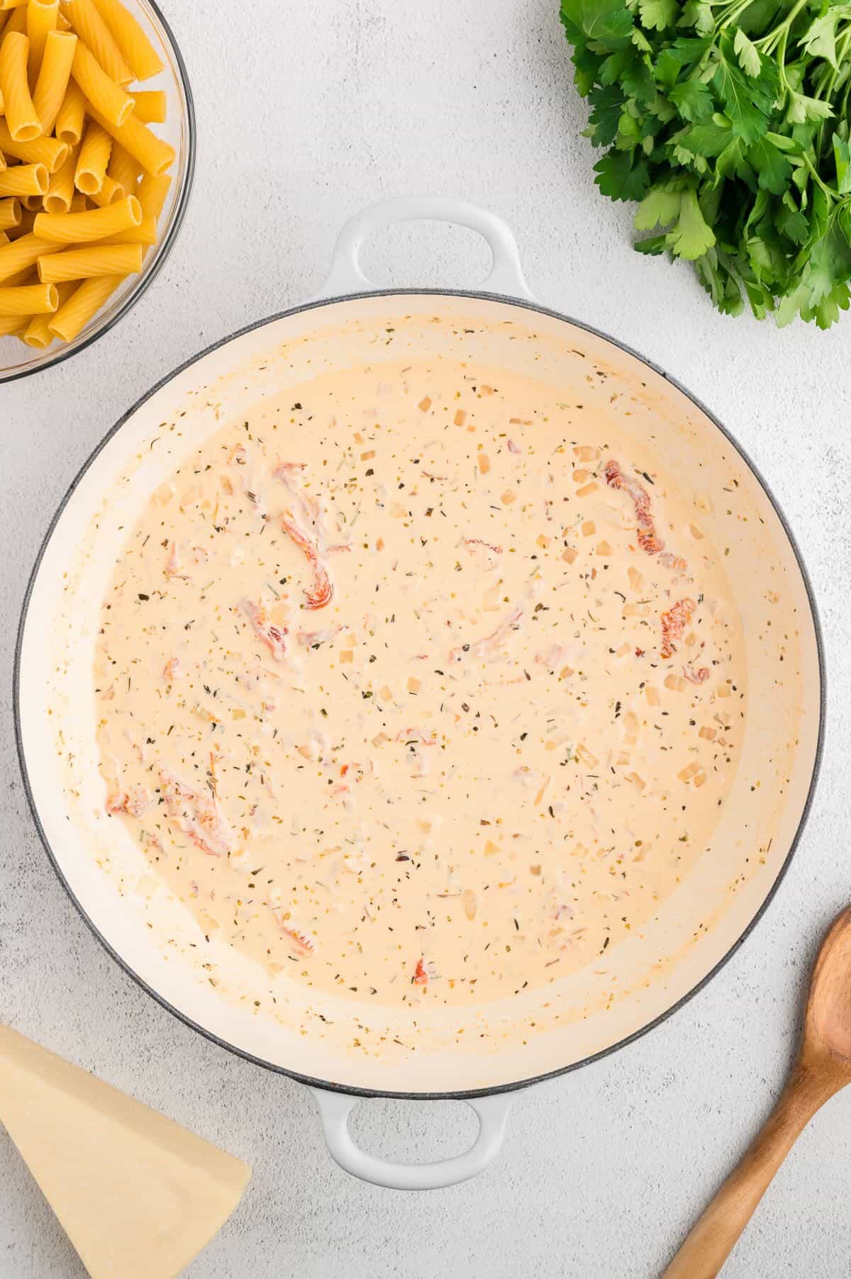 A creamy sauce made with heavy cream, Parmesan cheese and other ingredients in a skillet cooking. 