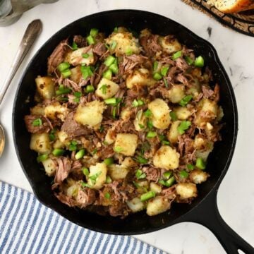 A cast iron skillet full of roast beef hash.