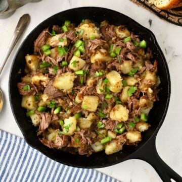 A cast iron skillet full of roast beef hash.