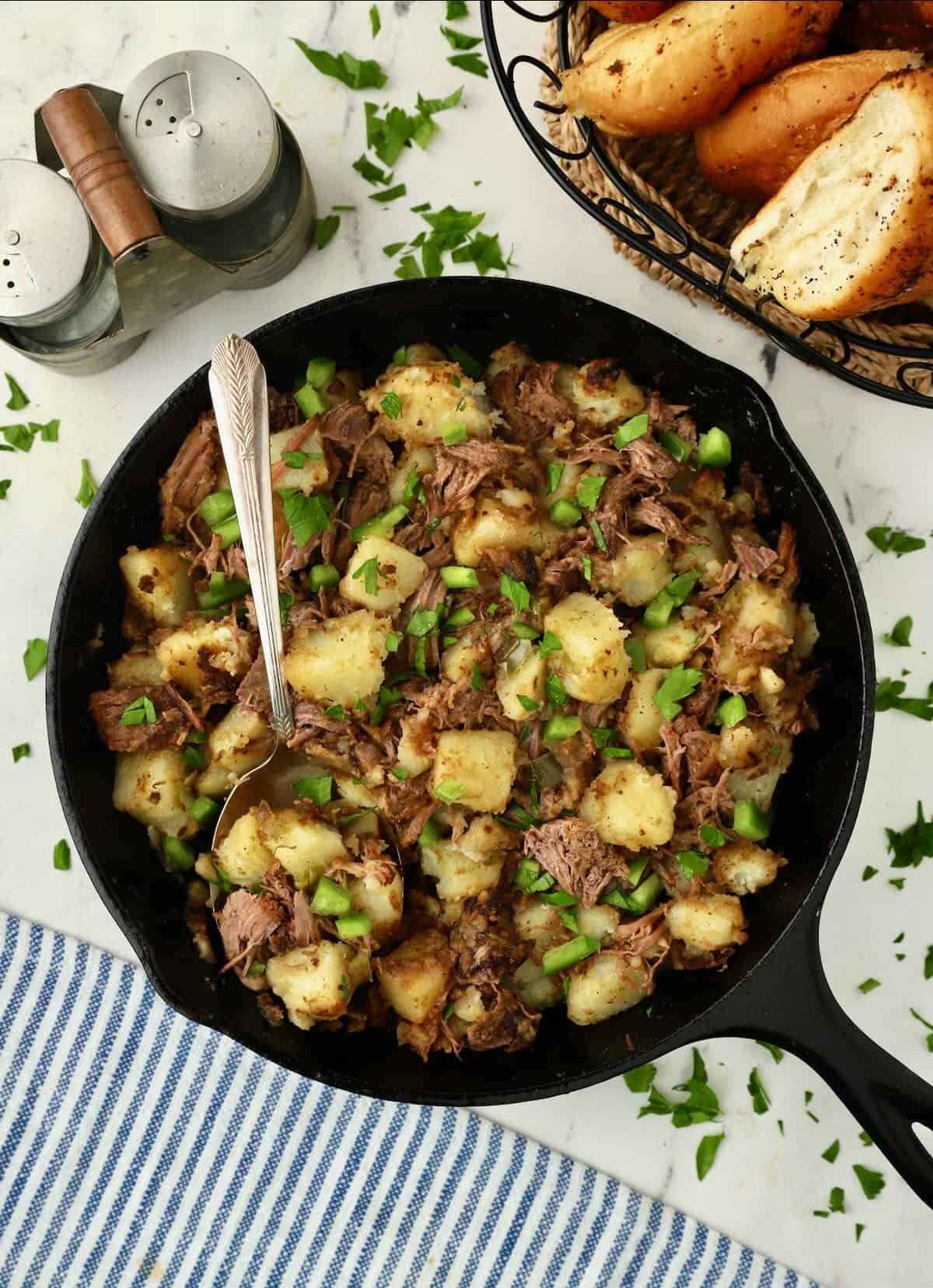 Roast Beef Hash in a cast iron skillet with a serving spoon. 