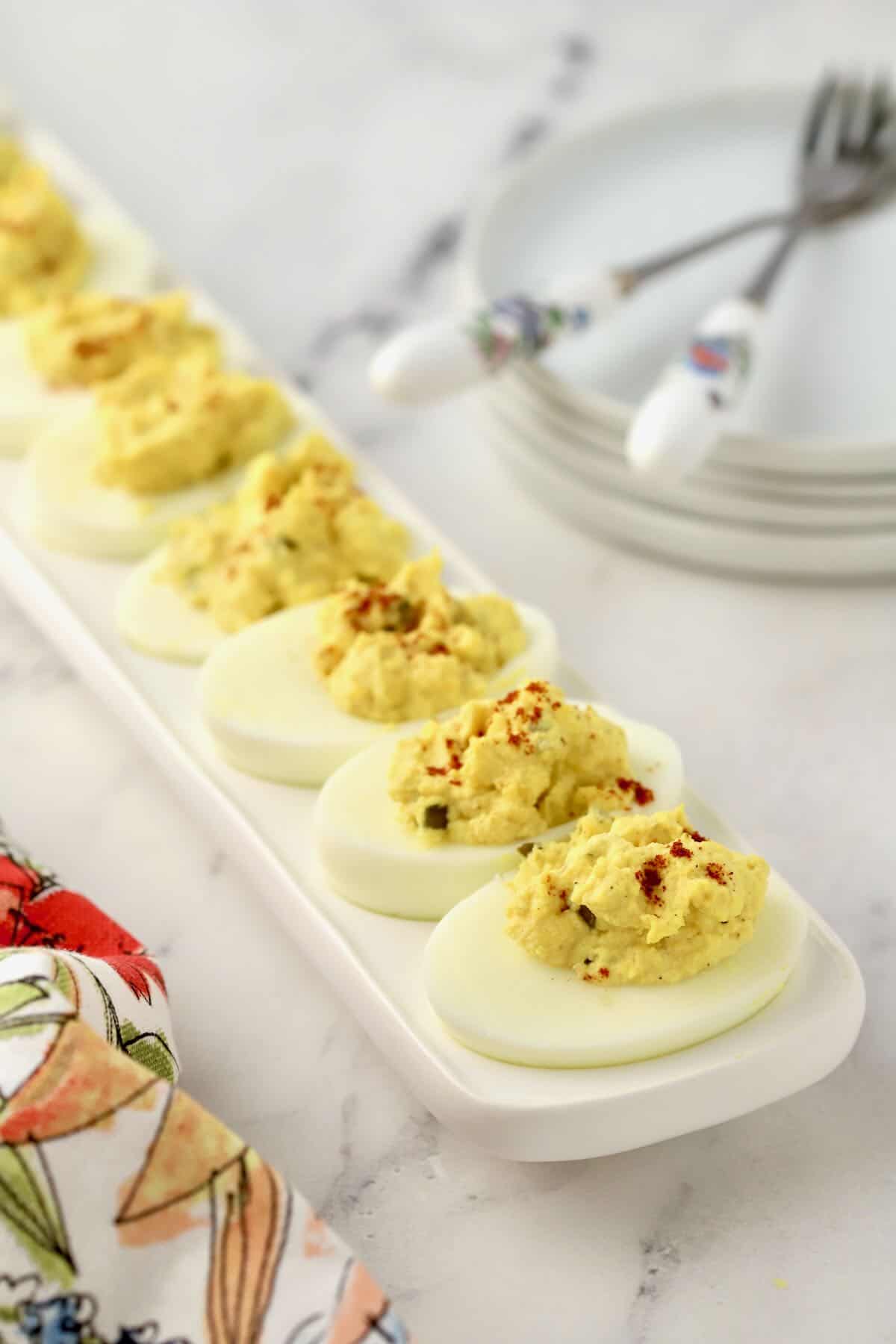 Deviled eggs topped with paprika on a long deviled egg holder.