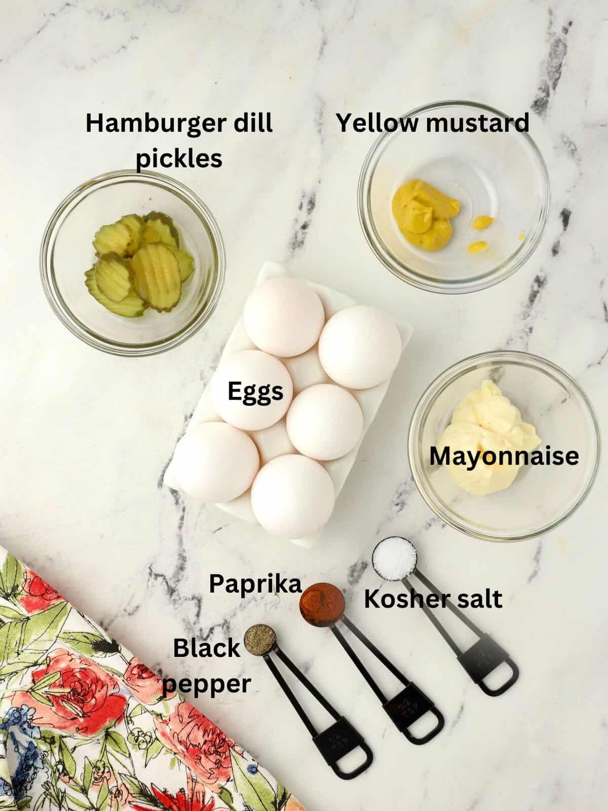 Ingredients for deviled eggs include eggs, pickles, mayonnaise, and mustard on a counter. 