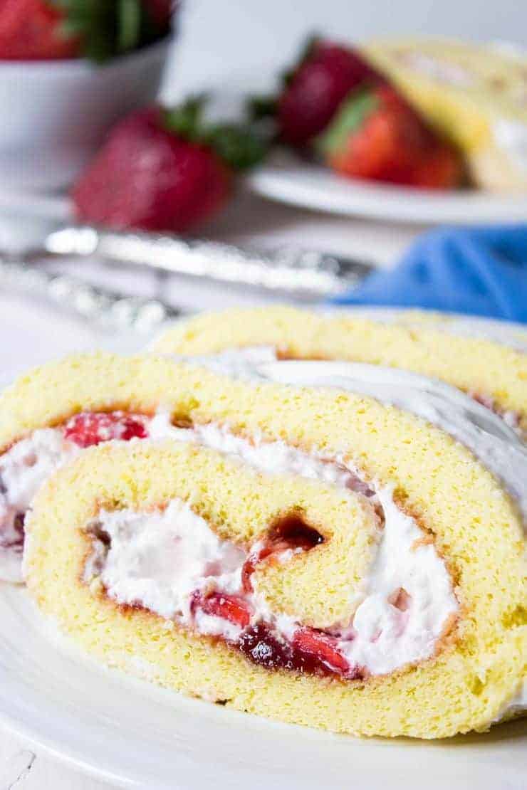 A slice of Strawberry Roll Cake full of whipped cream and strawberries. 
