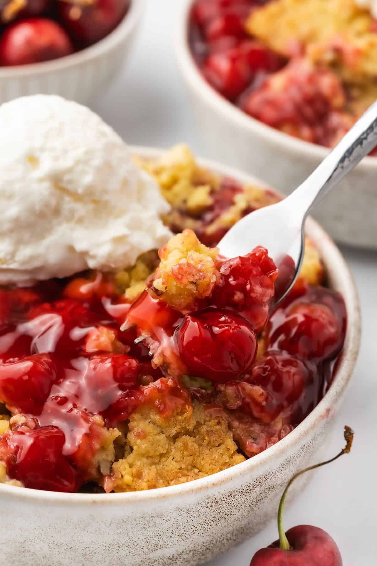 A serving of cherry cobbler, topped with a scoop of vanilla ice cream.