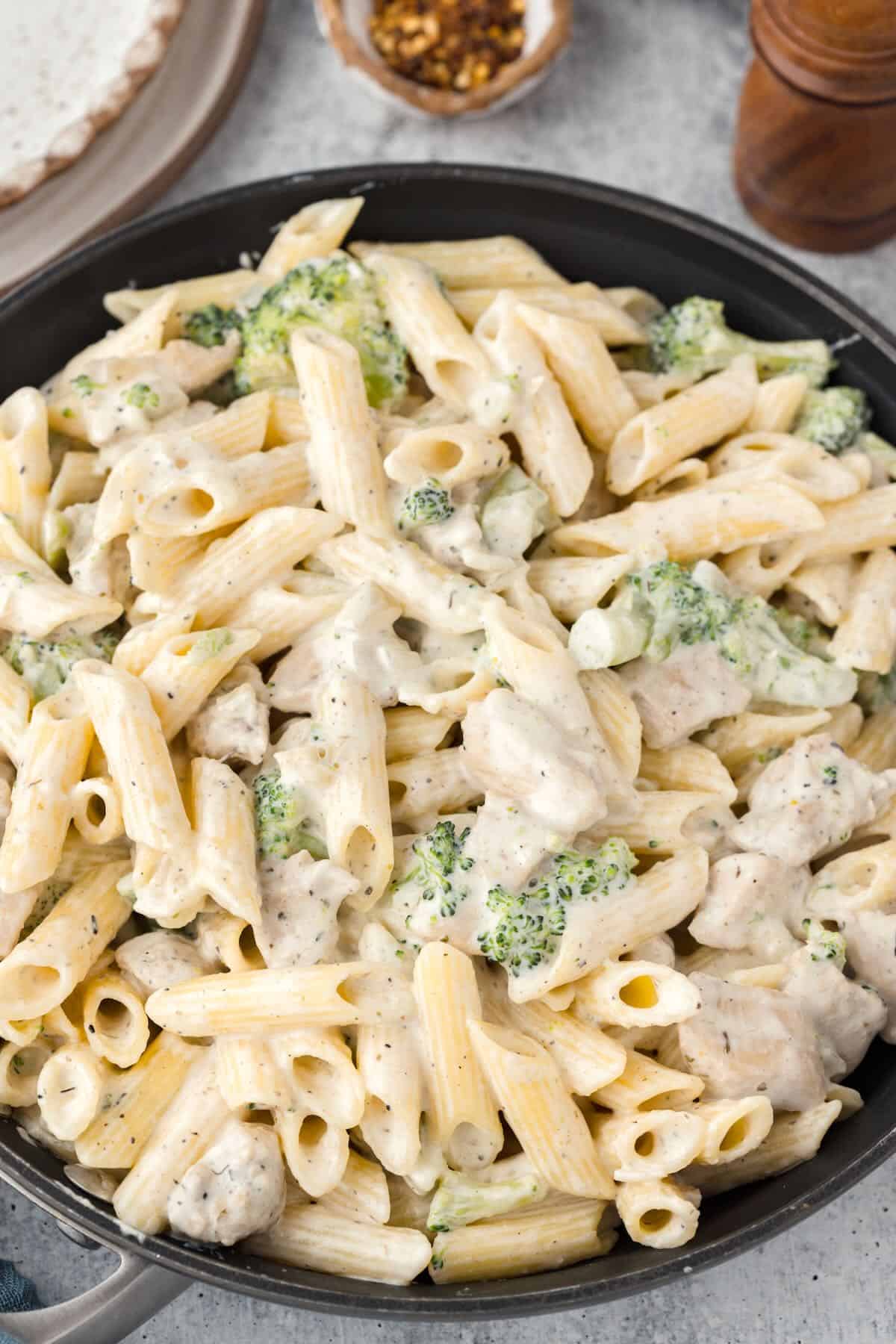 A skillet full of Chicken and Broccoli Pasta covered in a creamy sauce. 