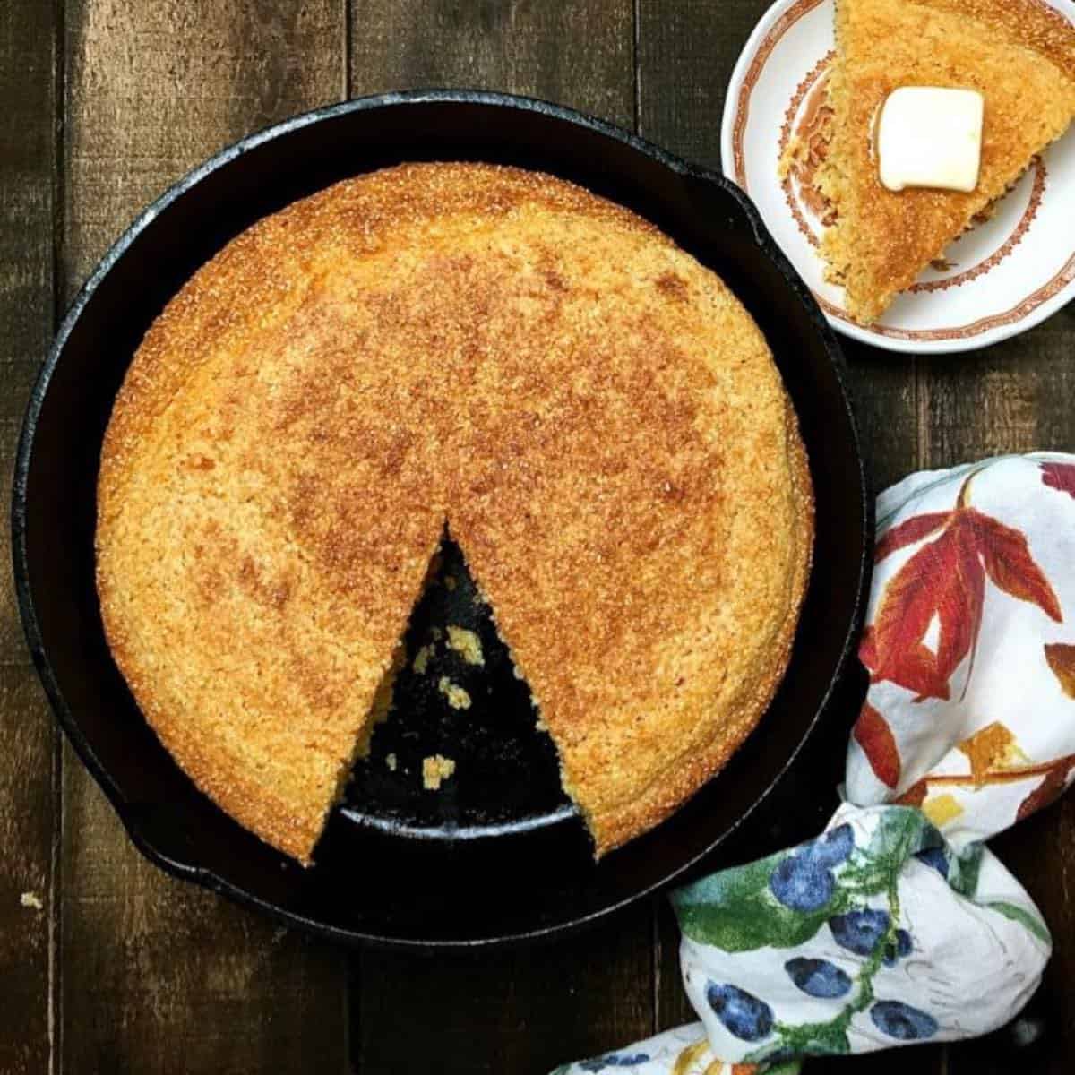 Cornbread in a cast iron skillet with a slice cut out.
