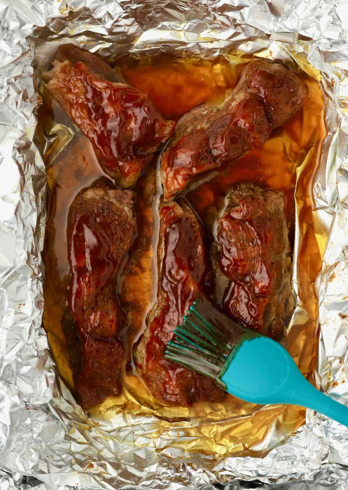 Brushing BBQ sauce on top of boneless ribs. 