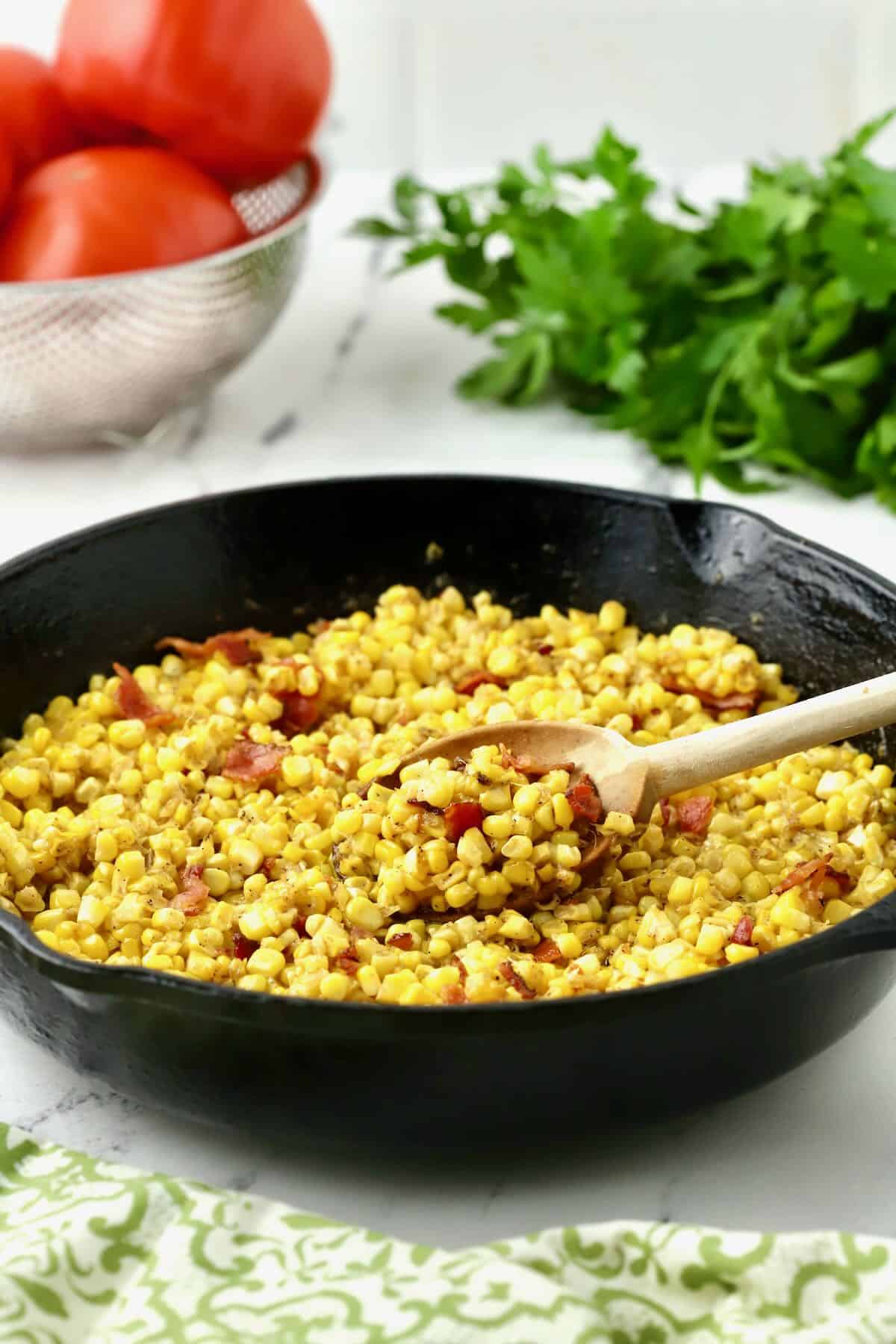 Fried corn topped with bacon in a cast iron skillet. 