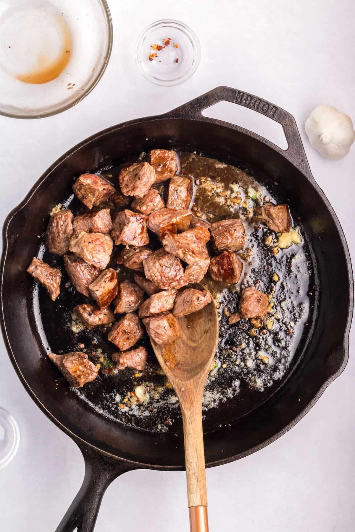 Cooked steak bites in a cast iron skillet. 