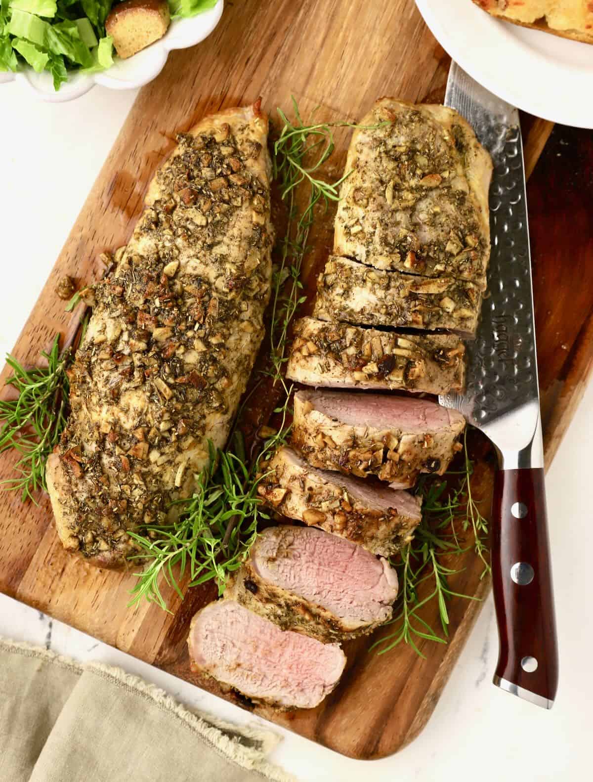 Sliced pork on a cutting board with a knife. 