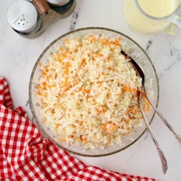 A large bowl of American Coleslaw containing shredded green cabbage and carrots.