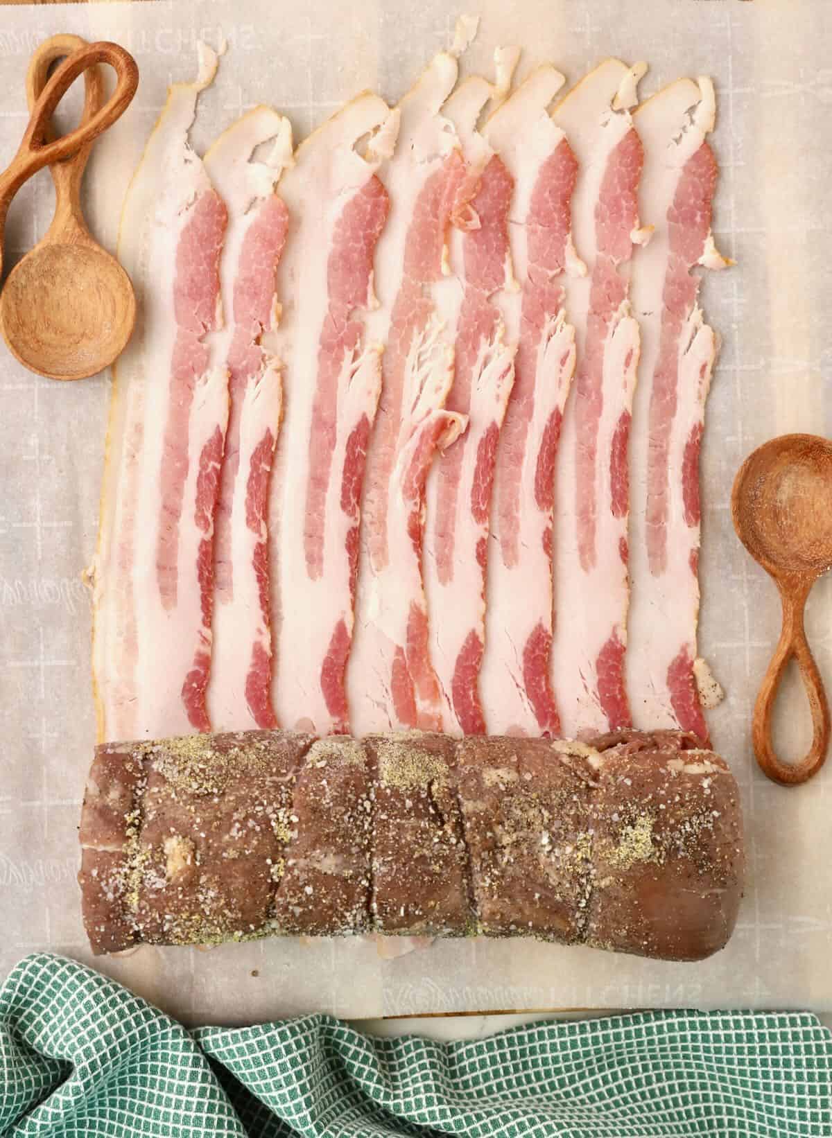 Slices of bacon next to a beef tenderloin.