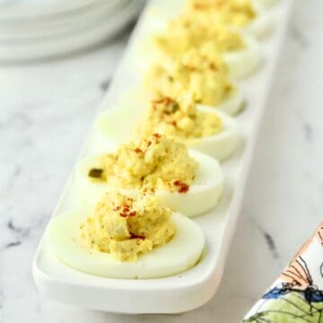 A deviled egg tray full of classic deviled eggs topped with a sprinkle of paprika.