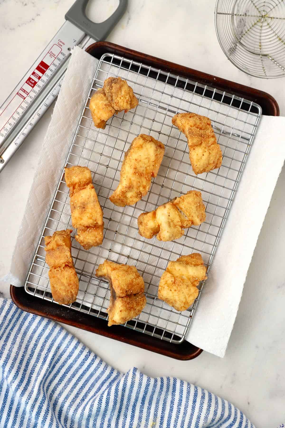 Fried red snapper fillets on a wire rack cooling. 