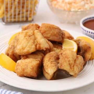 A plate of fried red snapper garnished with sliced lemons.