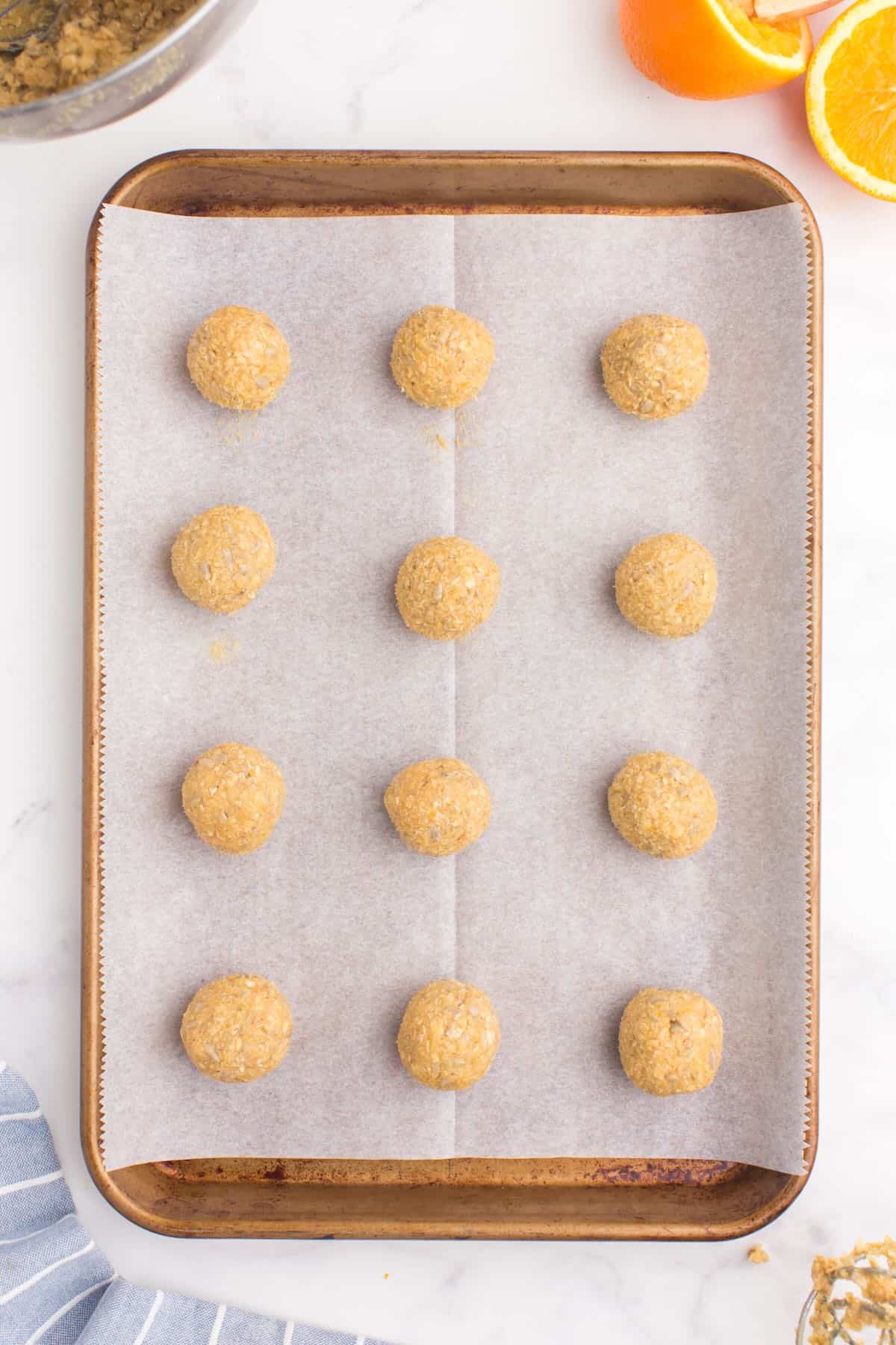 Balls of cookie dough on a baking sheet lined with parchment paper. 