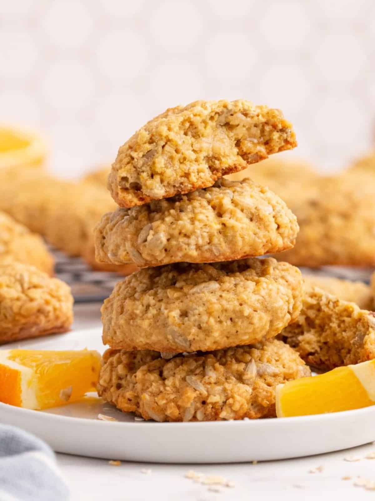 A stack of Sunflower Cookies on a white plate garnished with fresh orange wedges.