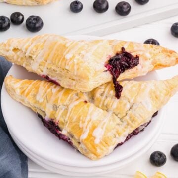 Two homemade blueberry turnovers on a white plate.