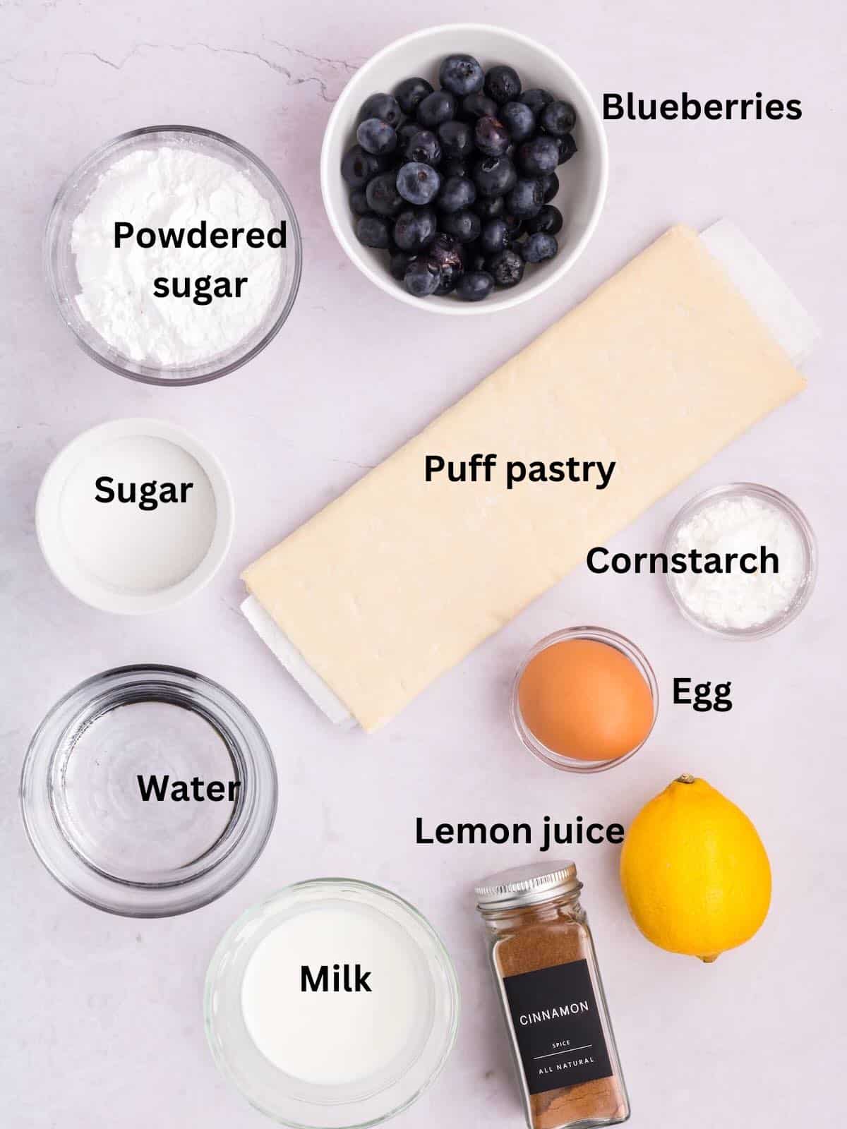 Ingredients to make blueberry turnovers including fresh blueberries and puff pastry. 