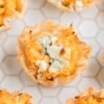 Buffalo Chicken Appetizers garnished with blue cheese on a white cutting board.
