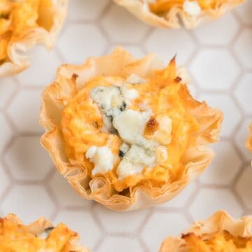 Buffalo Chicken Appetizers garnished with blue cheese on a white cutting board.
