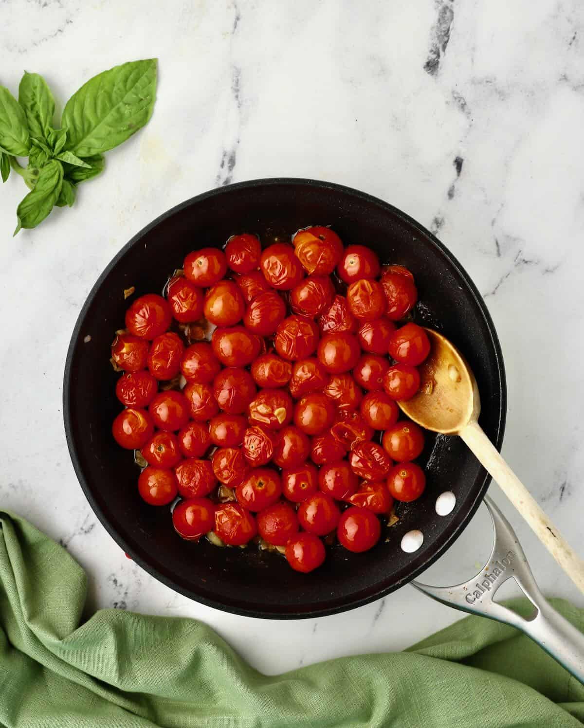 Cherry tomatoes cooking in a skillet. 