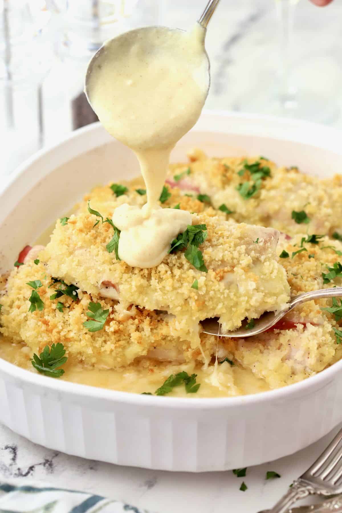 Baked chicken cordon bleu casserole with a spoonful of sauce poured over it.