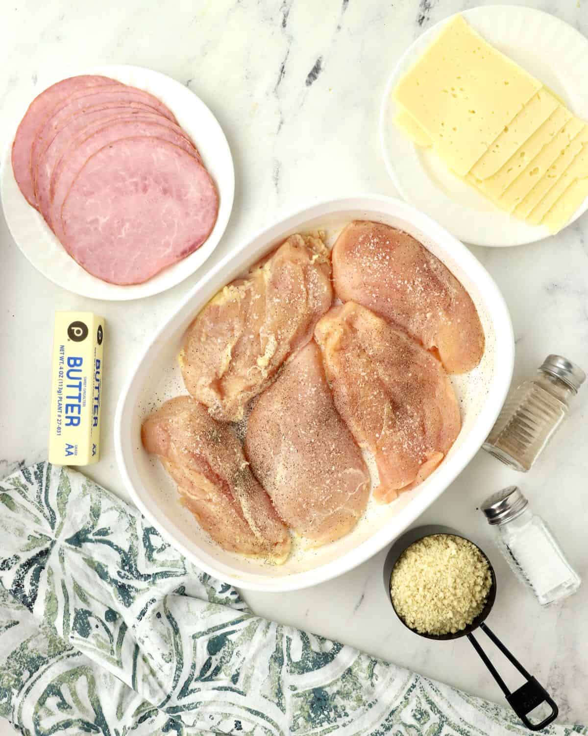 Chicken cutlets in a white baking dish with salt and pepper on them. 