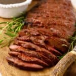A grilled London Broil sliced on a cutting board.